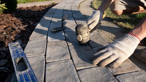 Laying paving stones for garden path with level and mallet