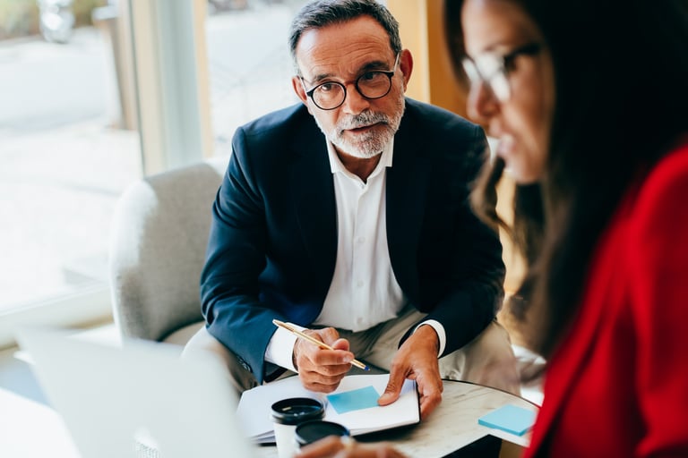 Senior Coastal Ridge Advisory Group advisor in focused strategic discussion with executive client, reviewing cost reduction and advisory planning