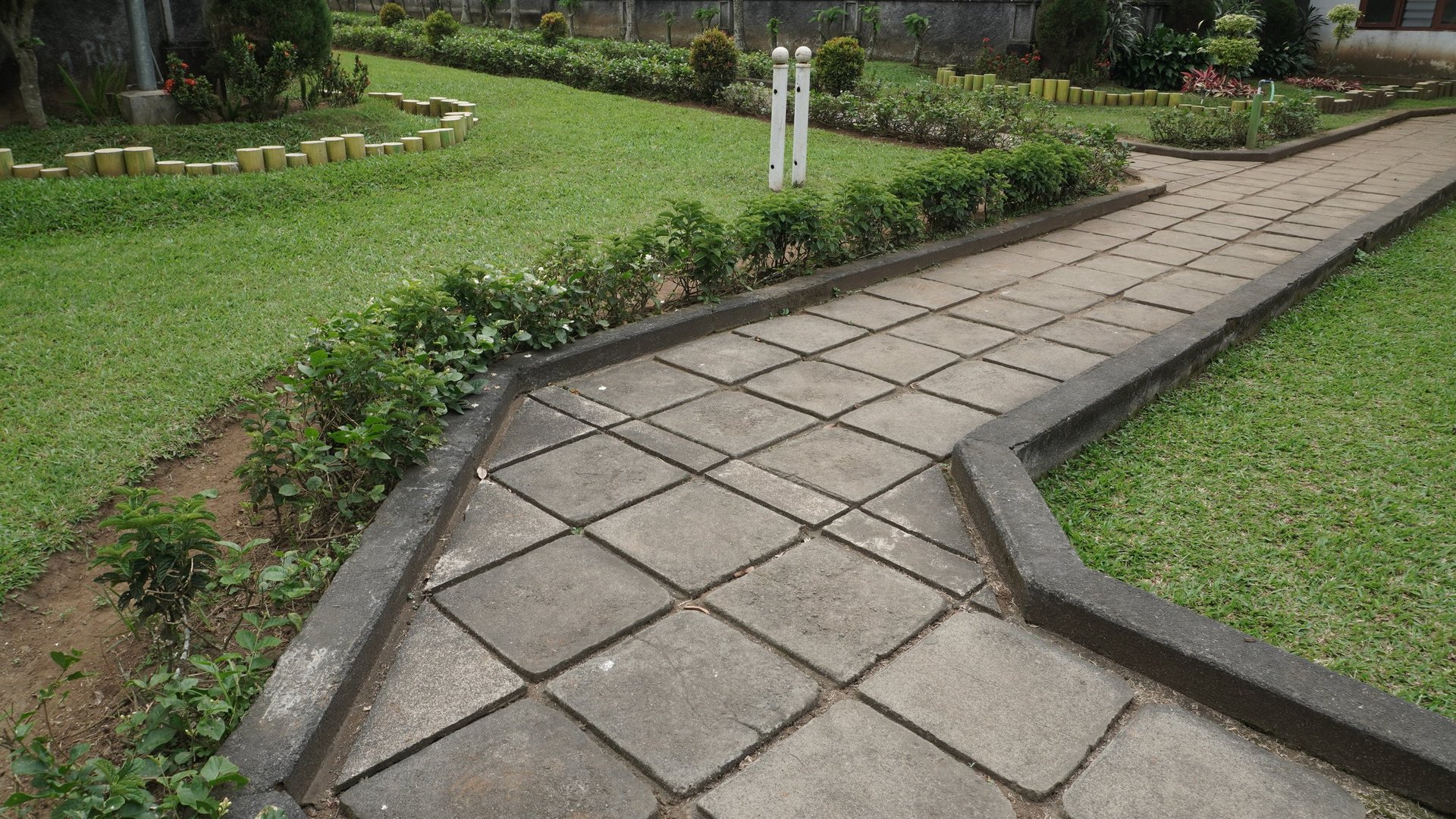 Well-maintained paved garden path with geometric stone patterns and lush green foliage