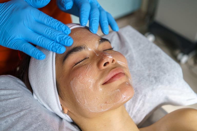 Young adult receiving professional facial treatment with anti-acne cream