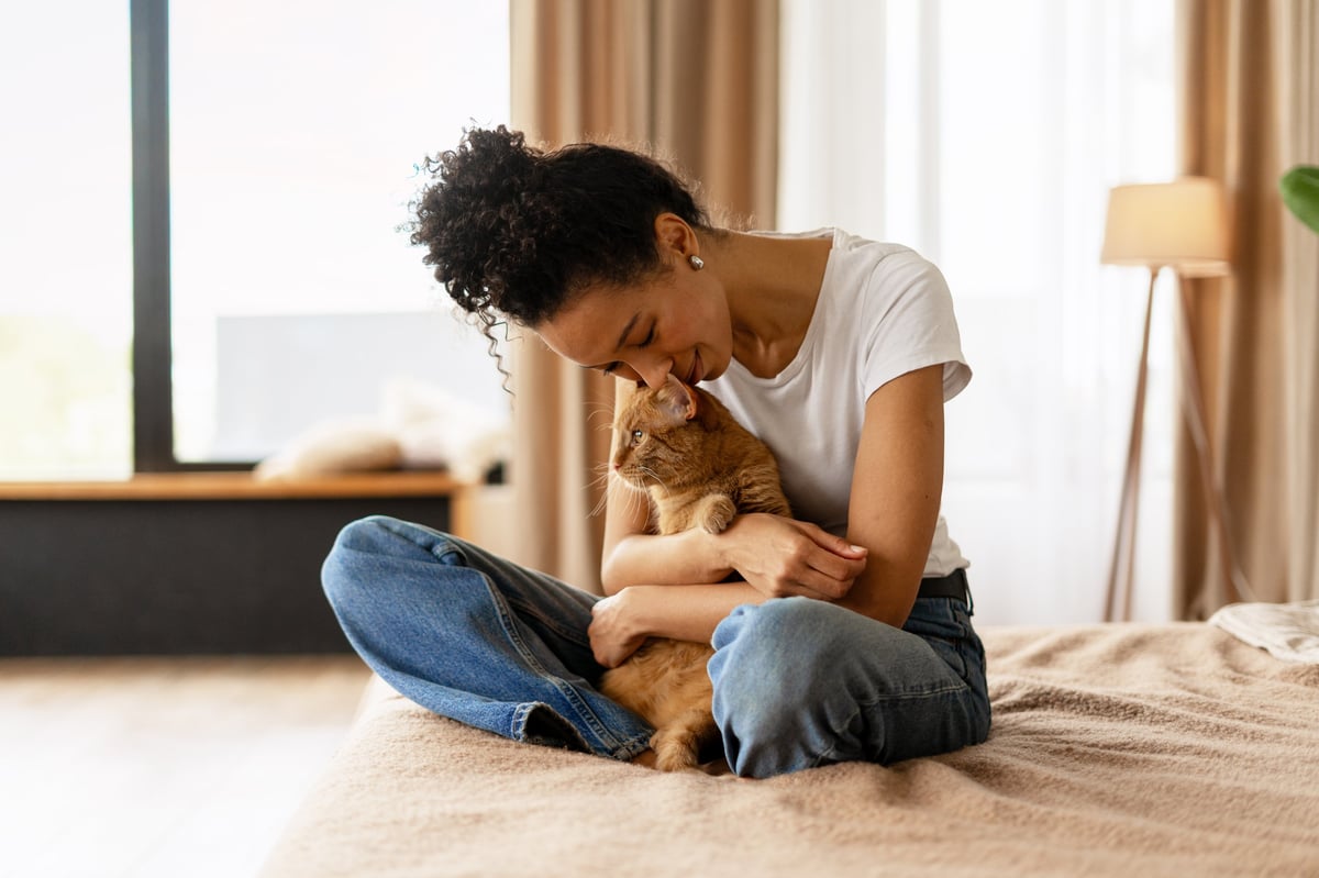 Woman with kitten and puppy cuddling together at home