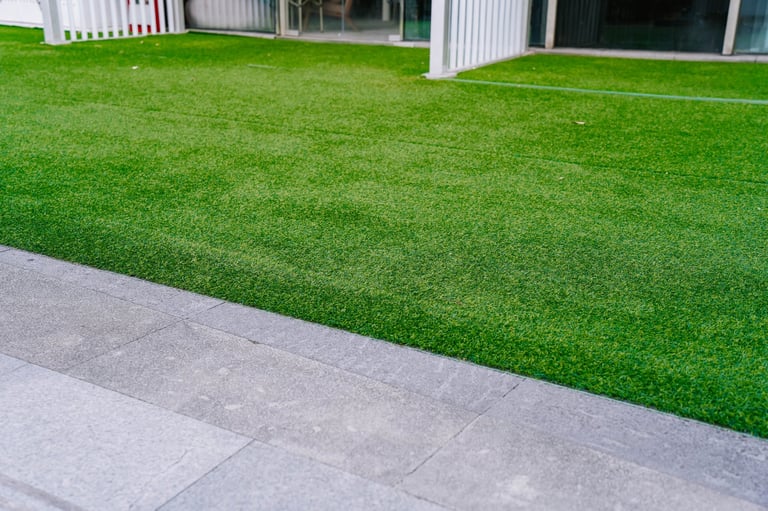Artificial grass lawn turf in the front yard of a modern building - low maintenance green lawn