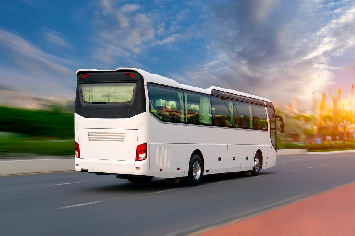 White tourist bus driving fast on highway through city
