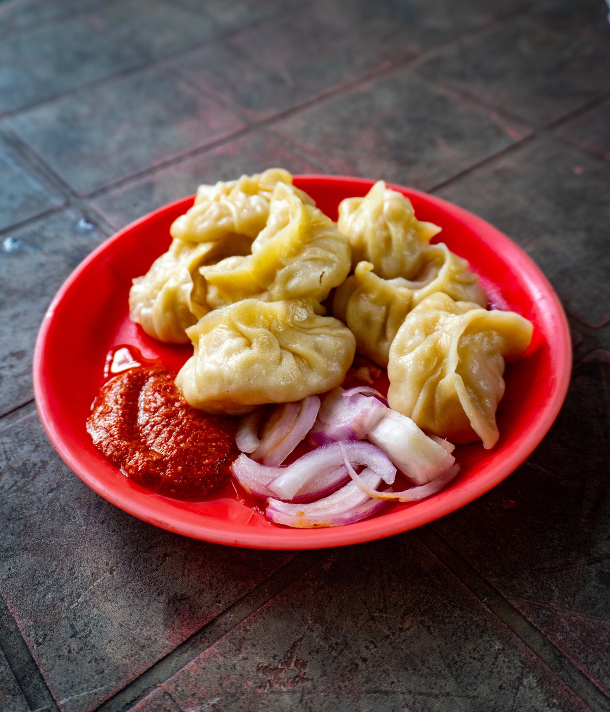 Hot momos served with spicy red chutney on a traditional plate
