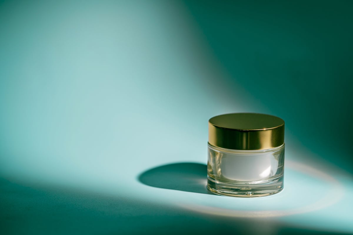 Glass skincare cream jar with golden lid — luxury formulation