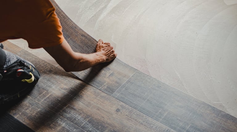 Construction worker installing baseboard or flooring plank