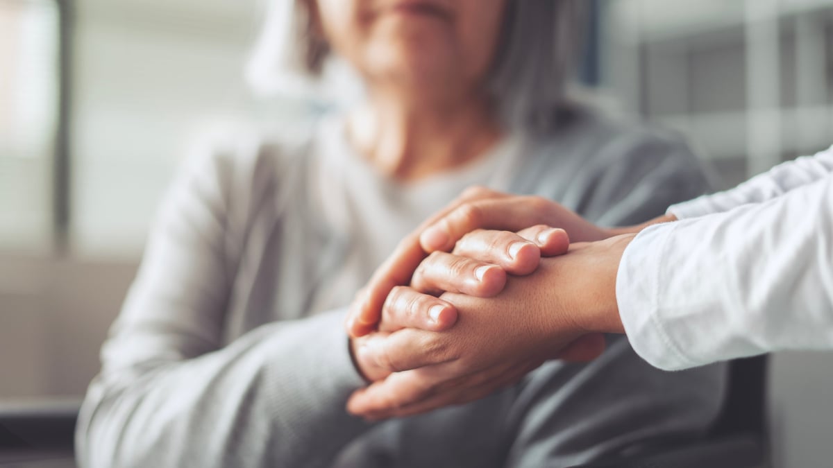 Family member holding hands with elderly loved one, supported by care coordination
