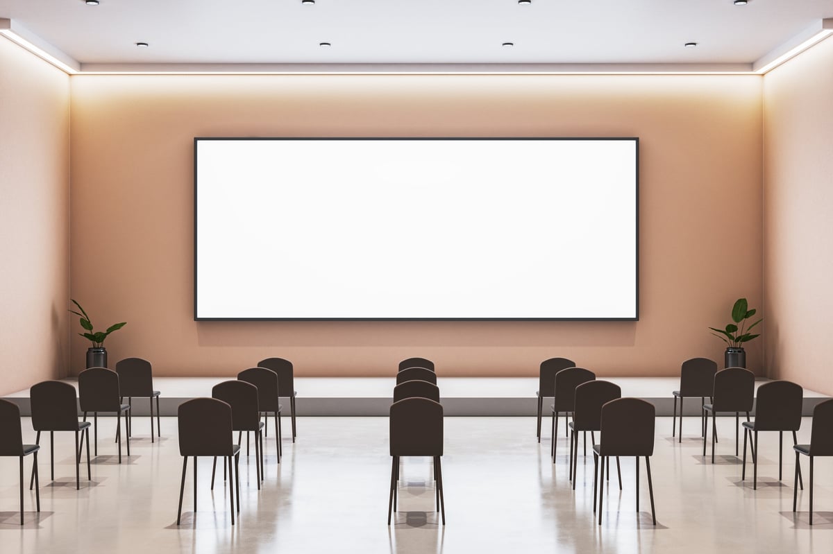 An empty modern conference auditorium with rows of chairs facing a lit stage