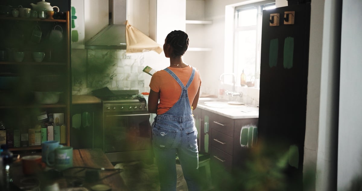Woman in kitchen with paintbrush planning renovation
