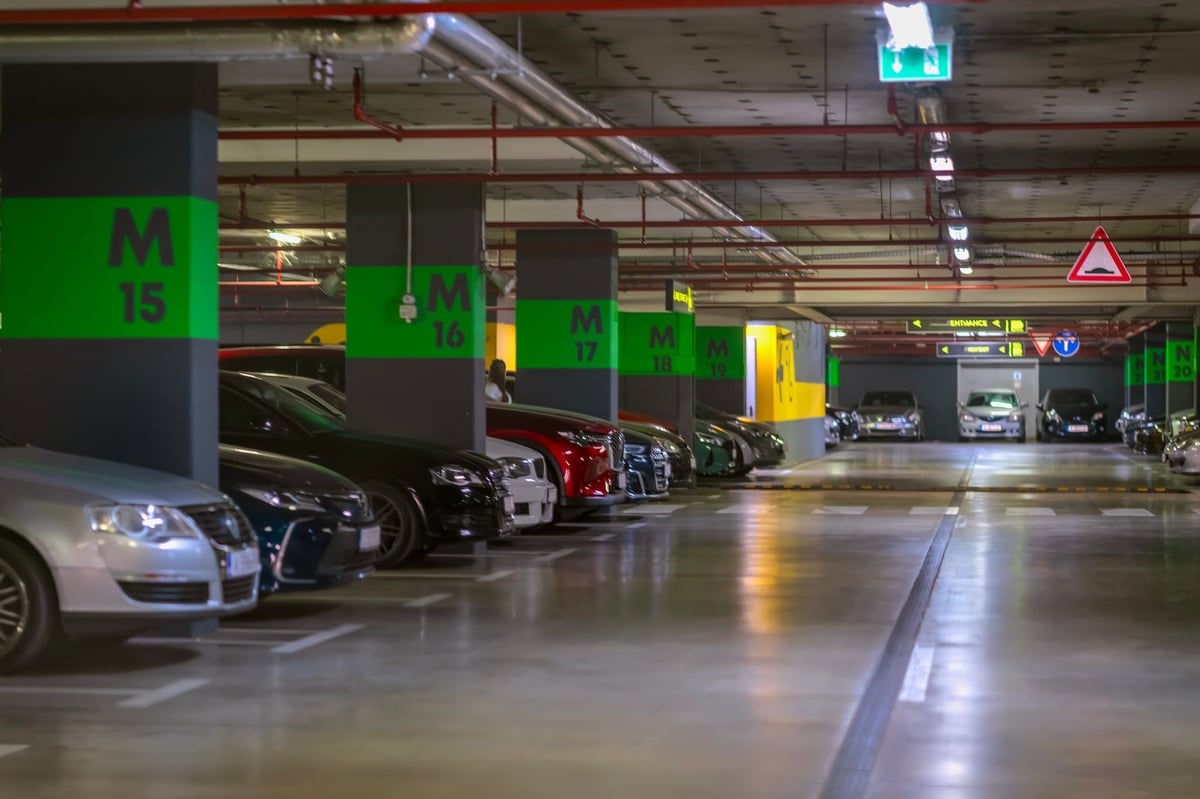 Underground Seattle parking garage with green section markings and a row of parked cars