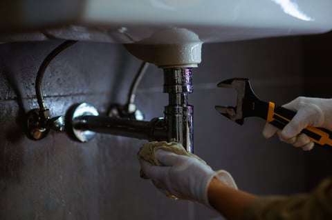 Plumber working on plumbing under a sink