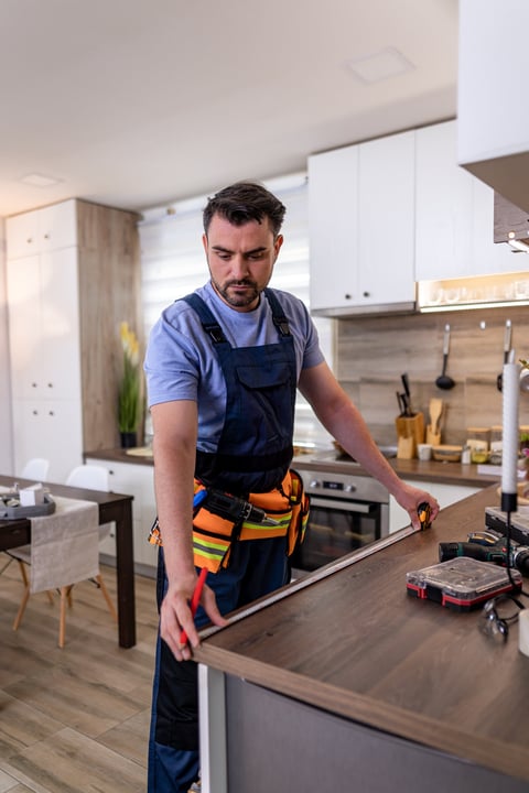 Professional measuring and fitting cabinetry in modern kitchen