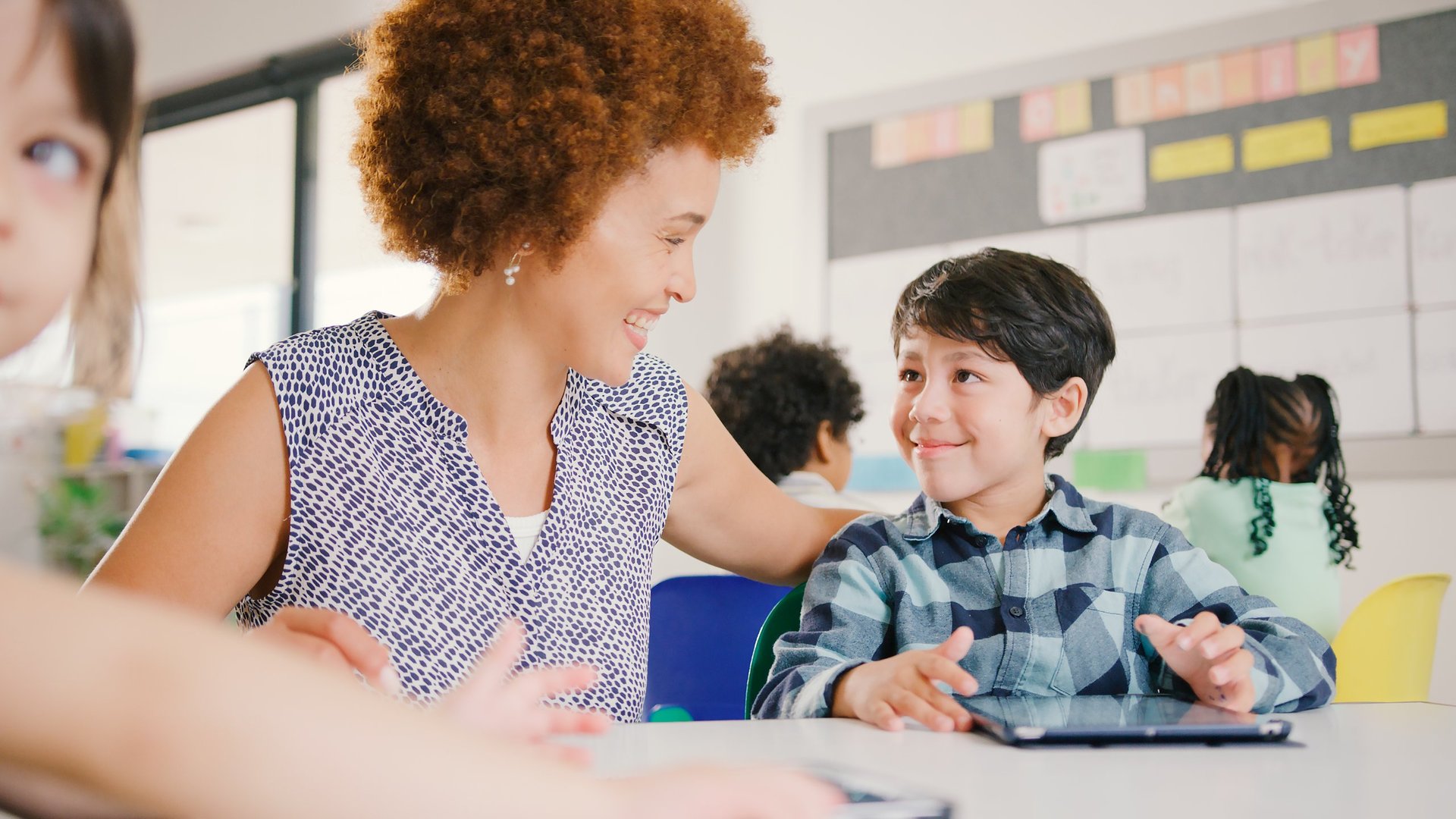 A caring teacher engaging a diverse group of elementary students during a classroom activity