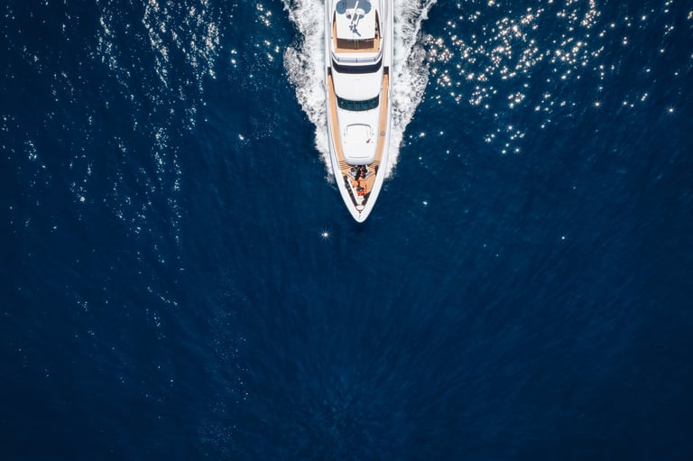 Aerial overhead view of a bow of a luxury yacht cruising with speed over ocean