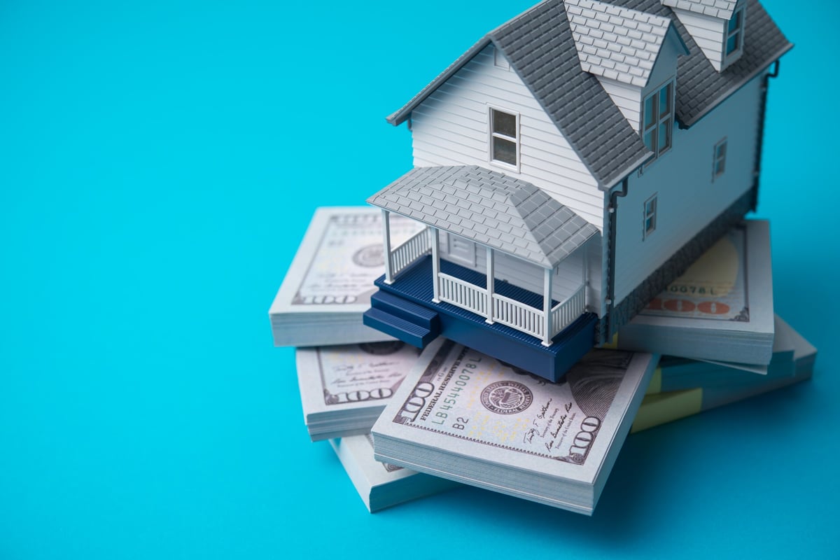 House model on a heap of US dollar banknotes, representing home equity, property value and real estate financing