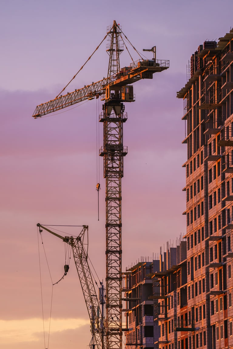 Construction cranes at sunset