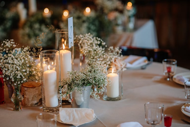 Close-up of a wedding table centerpiece with lit candles, baby's breath flowers, and elegant table settings
