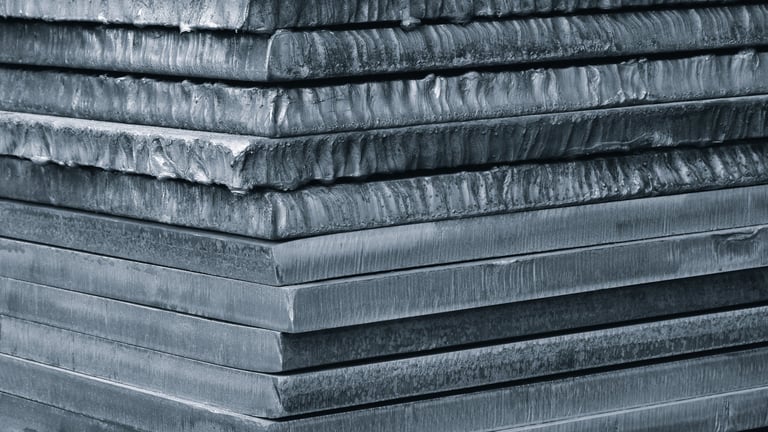 Stack of laser-cut metal plates in industrial warehouse