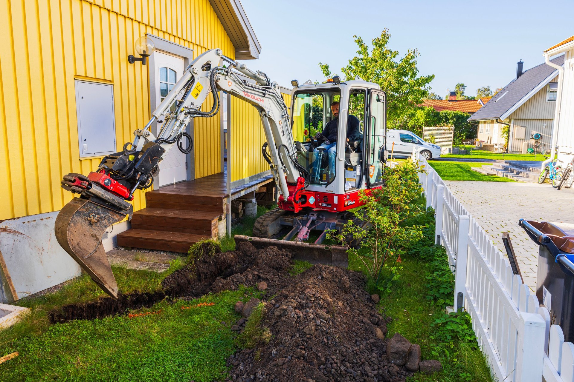 A Takeuchi TB225 compact excavator digging a trench on a residential job site, the kind of equipment CBB Group arranges financing for