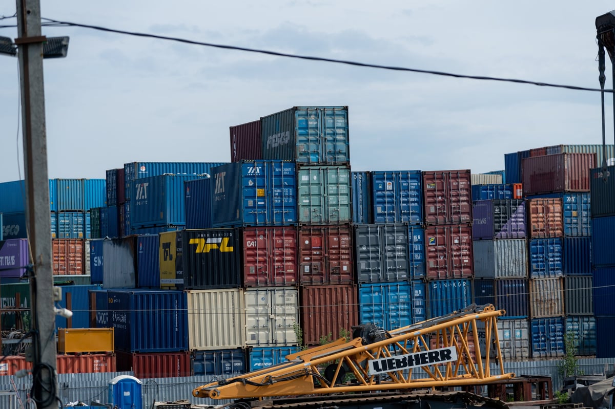 Workers maneuvering container units at a shipping yard
