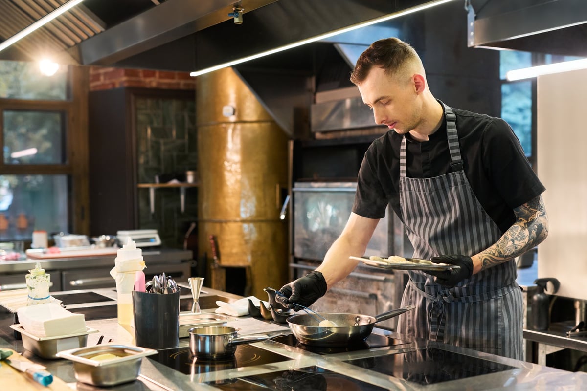Chef profesional preparando alimentos en cocina industrial con equipo STEELHAUS