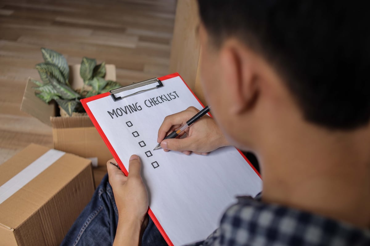 Mann bereitet Umzug vor mit Checkliste und Klemmbrett