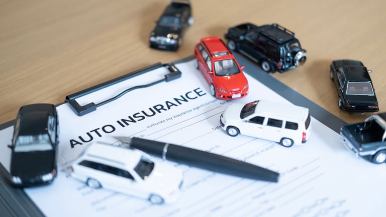 Auto insurance concept with miniature cars and pen on wooden desk