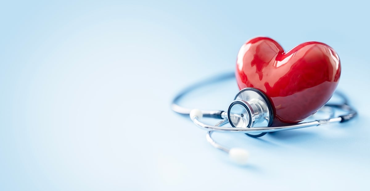 Corazón anatómico y estetoscopio sobre fondo azul, concepto de diagnóstico cardiovascular