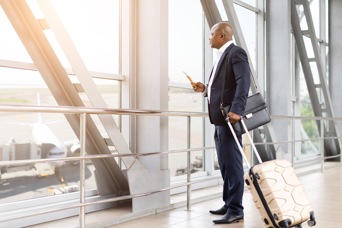 International investor at an airport window holding a passport before departure