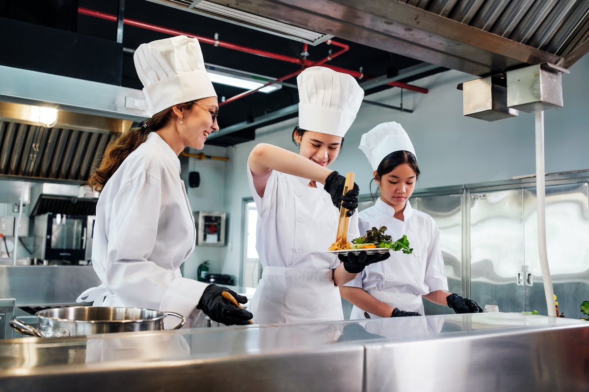 Students working together in a culinary kitchen learning food preparation and presentation