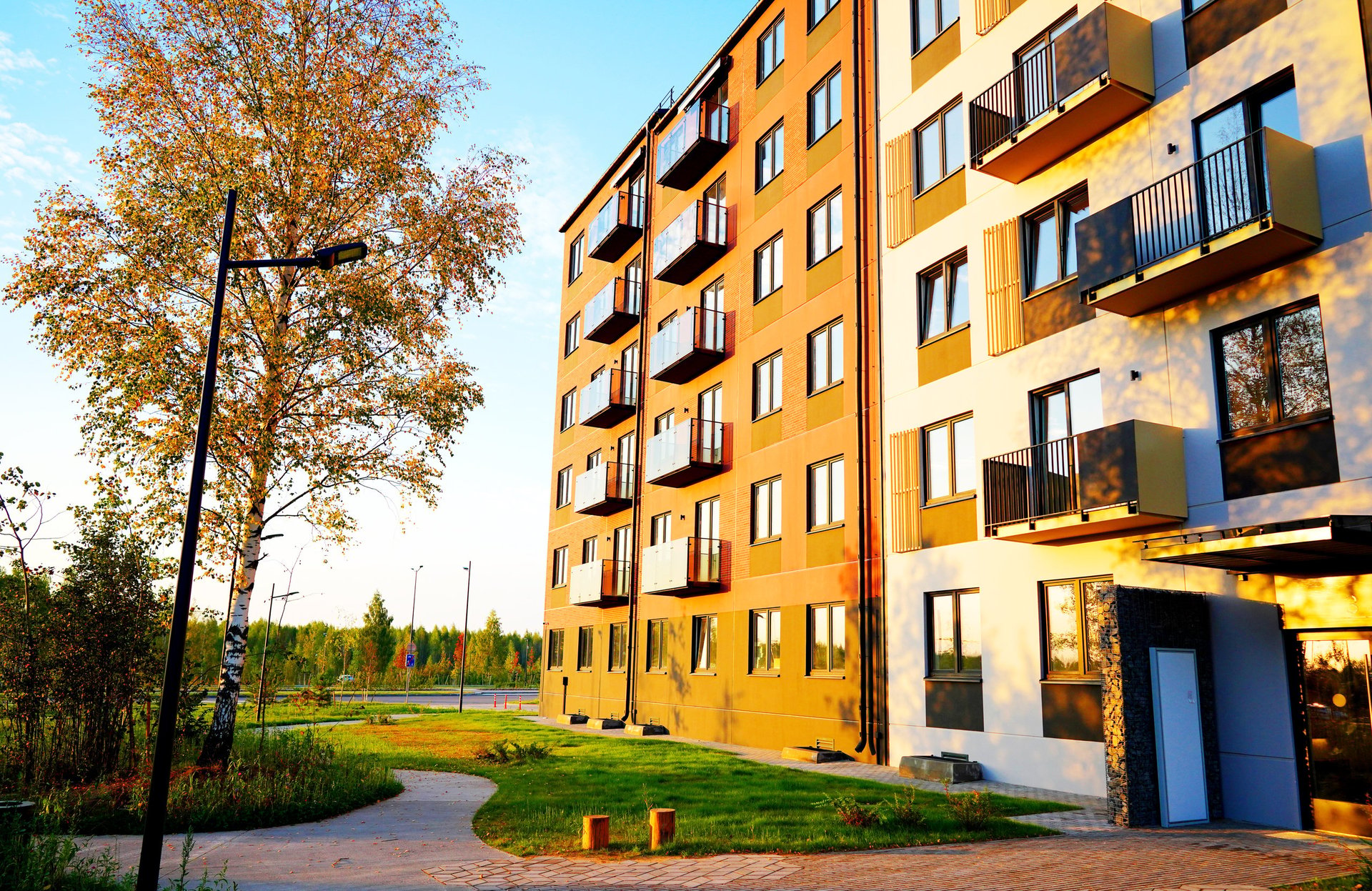Edificio residencial moderno con áreas verdes y entrada iluminada al atardecer