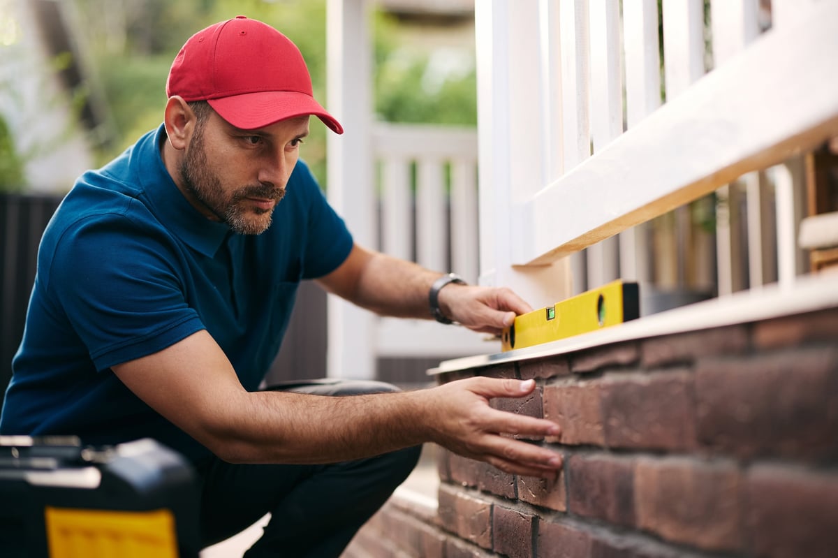 Construction worker using level while repairing a porch wall