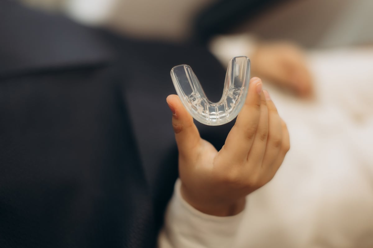 Hand holding a transparent custom dental nightguard, protective guard for healthy teeth