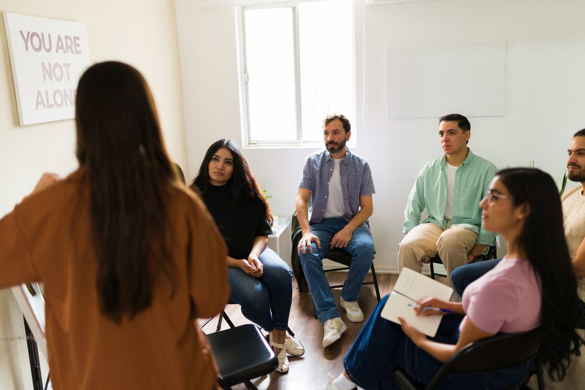 Caregiver support group meeting with people sharing experiences in a supportive circle