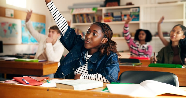 Elementary students raising their hands during a Lighthouse classroom lesson