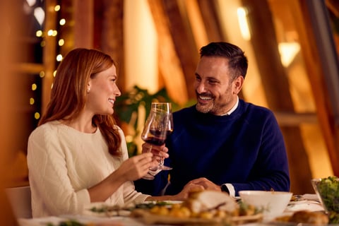Two adults enjoying a cheerful toast with wine and cozy lighting