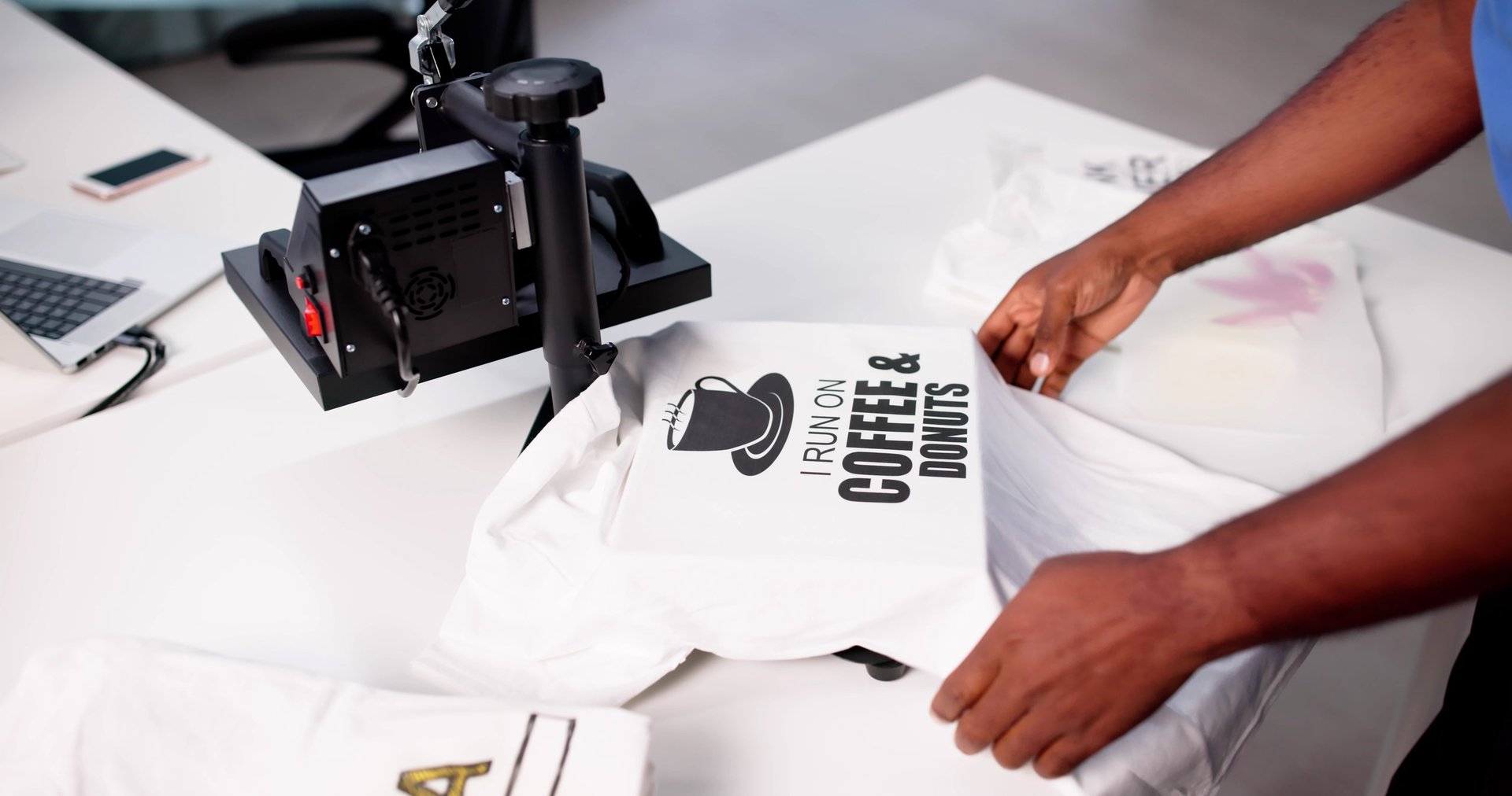 Man screen printing custom t-shirt at heat press