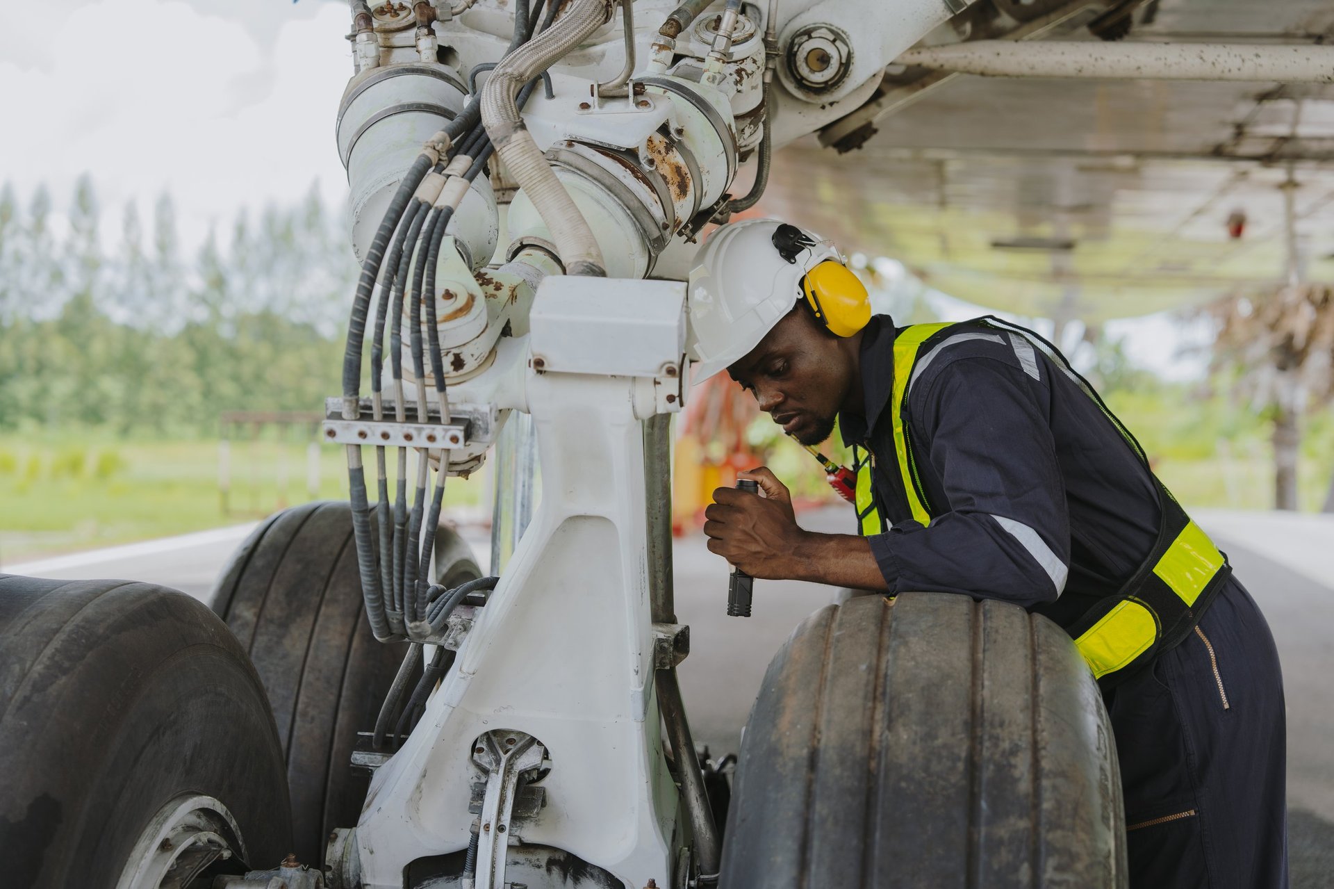 Mechanics inspect the engines of a large plane before takeoff at a summer airport