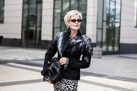 Woman standing in black jacket and leopard print dress