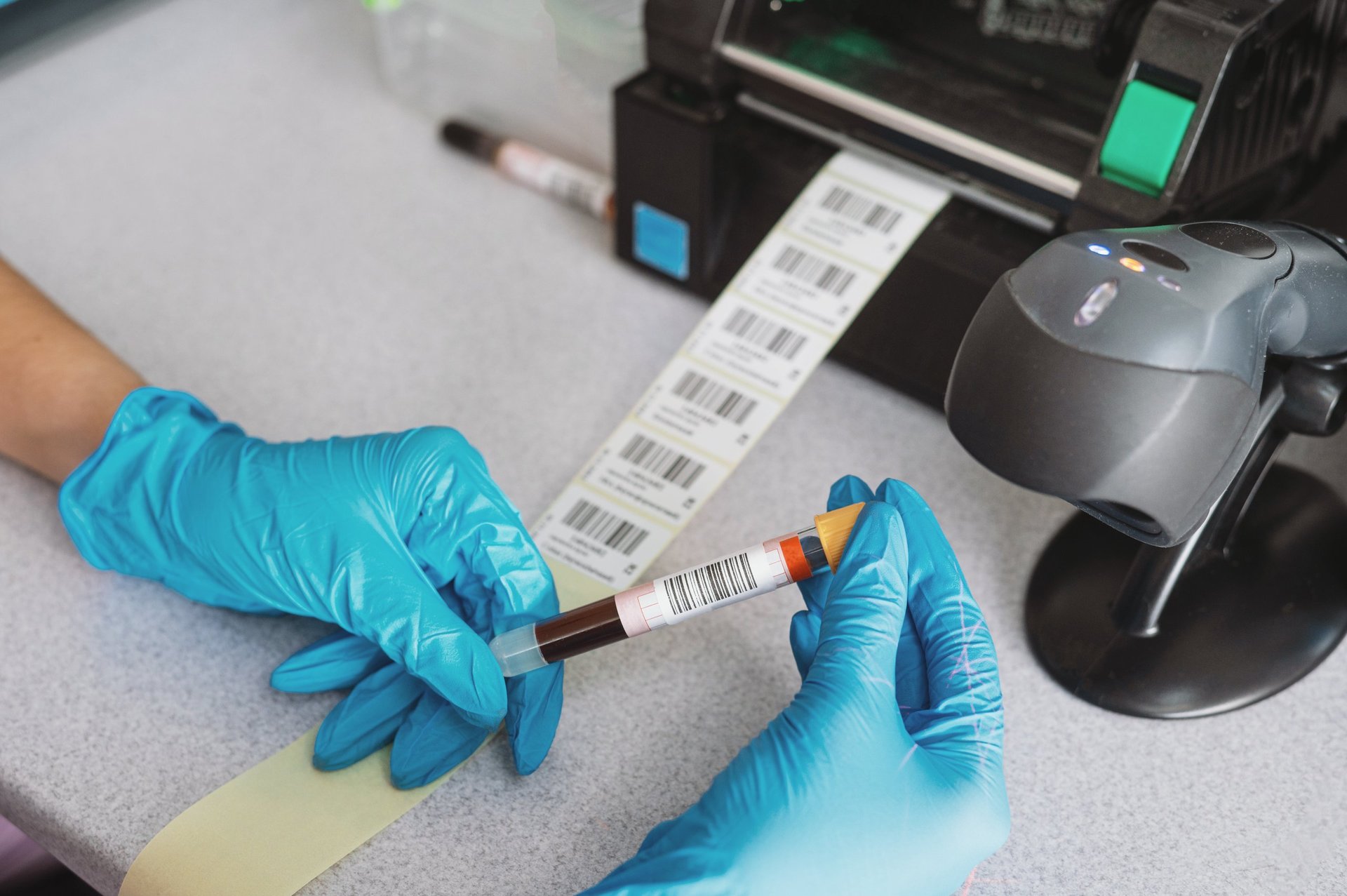 Close up of laboratory technics with equipment and tubes near computer doing barcodes for tubes