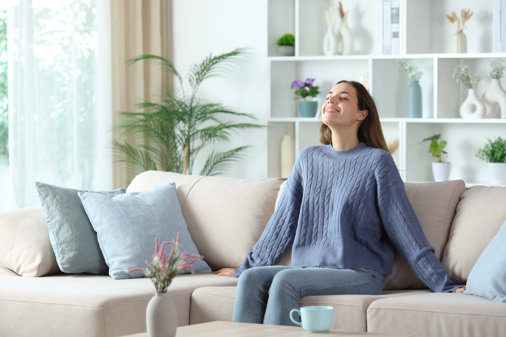 Happy homeowner relaxing on a sofa in a bright, freshly cleaned living room