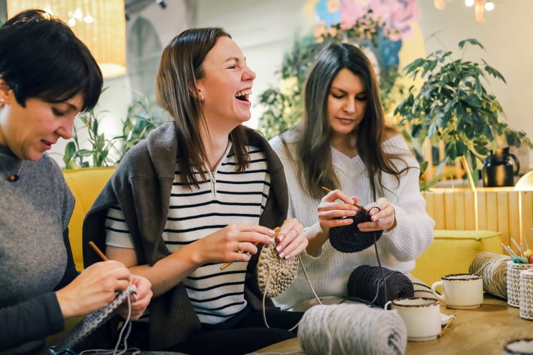 Tres mujeres tejiendo juntas con lana en un taller creativo acogedor