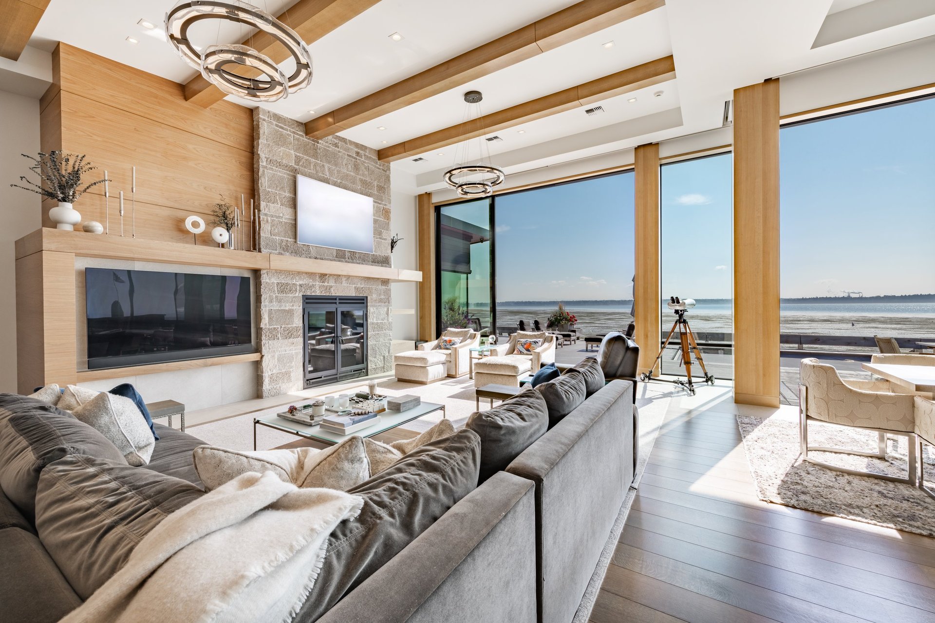 Lujosa sala contemporánea con ventanales de piso a techo, vista al mar, chimenea de piedra, piscina infinita y diseño arquitectónico premium