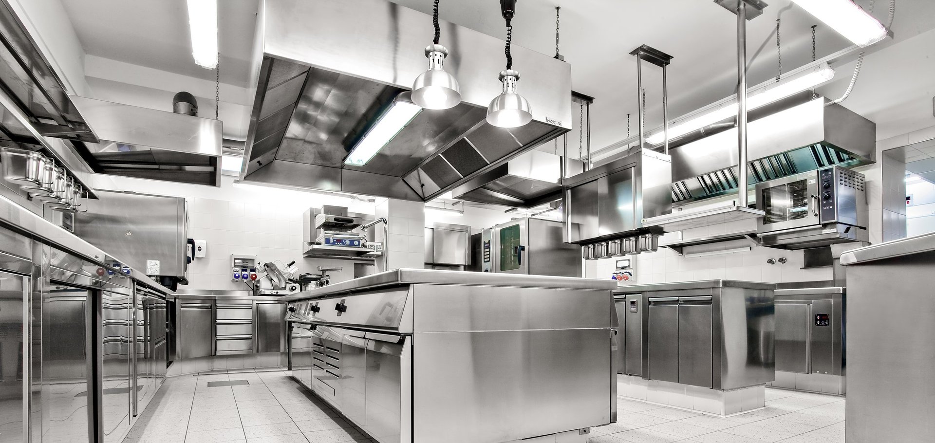 Spacious commercial kitchen with ovens, stoves, prep counters, and ventilation hoods — ideal for high-volume culinary operations