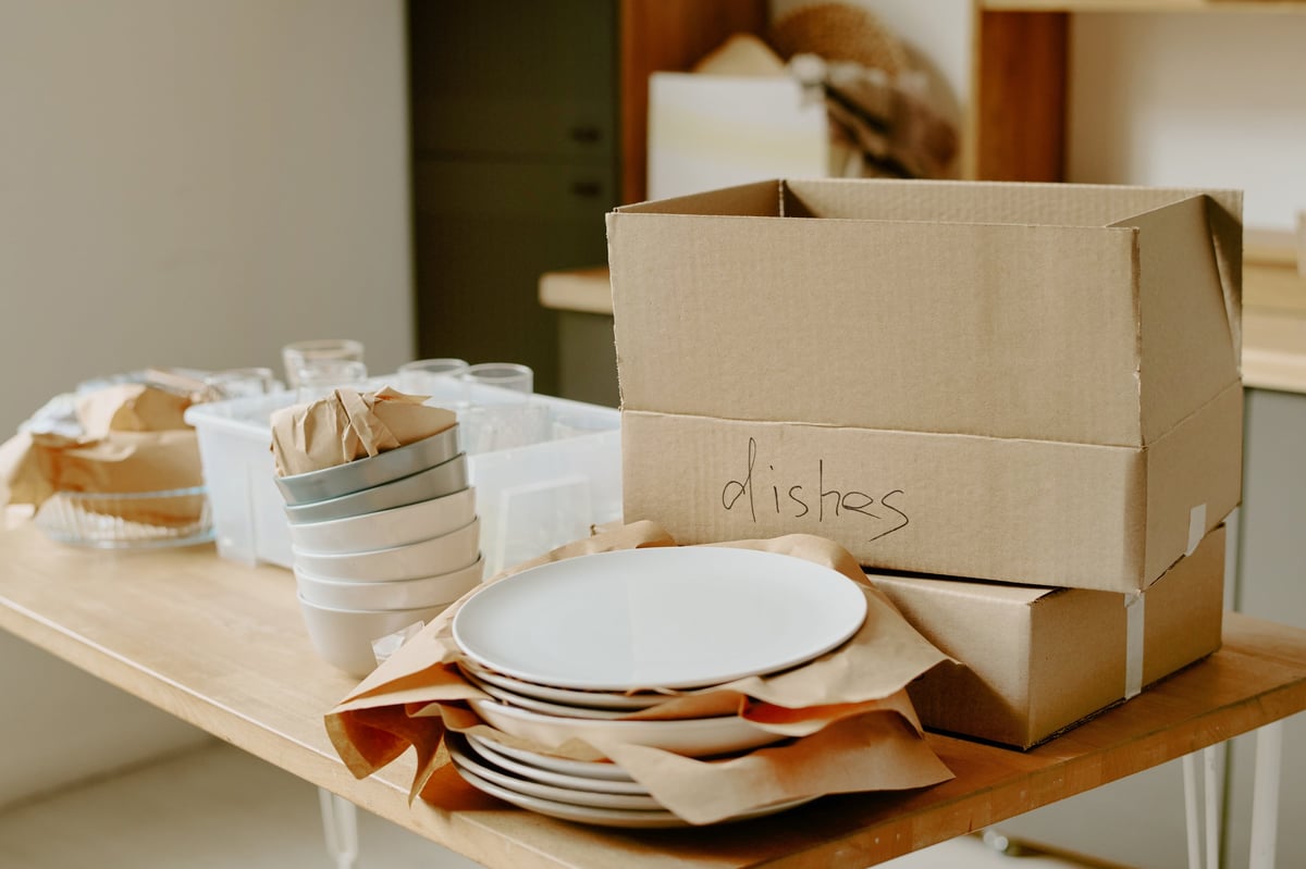 Umzugskartons mit sorgfältig verpacktem Geschirr auf einem Holztisch