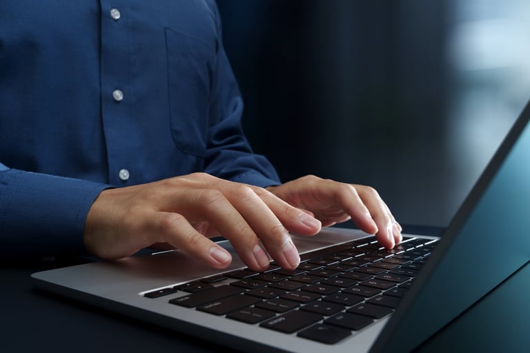 Hände tippen auf einer Laptop-Tastatur in modernem Arbeitsumfeld
