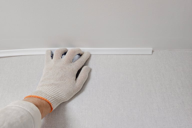 Worker installing corner trim at wall and ceiling junction, close up