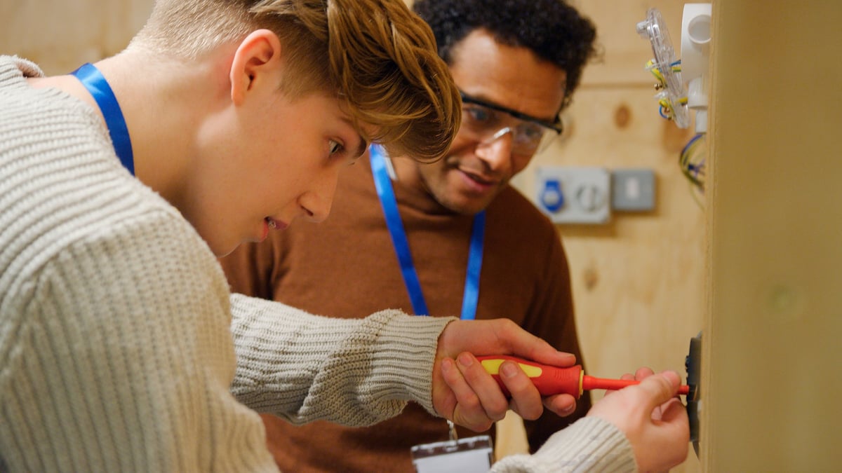 Students learning electrical concepts under qualified supervision with appropriate safety equipment