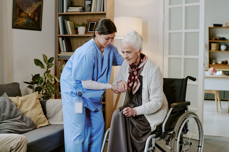 Nurse holding hand of elderly woman in wheelchair at home