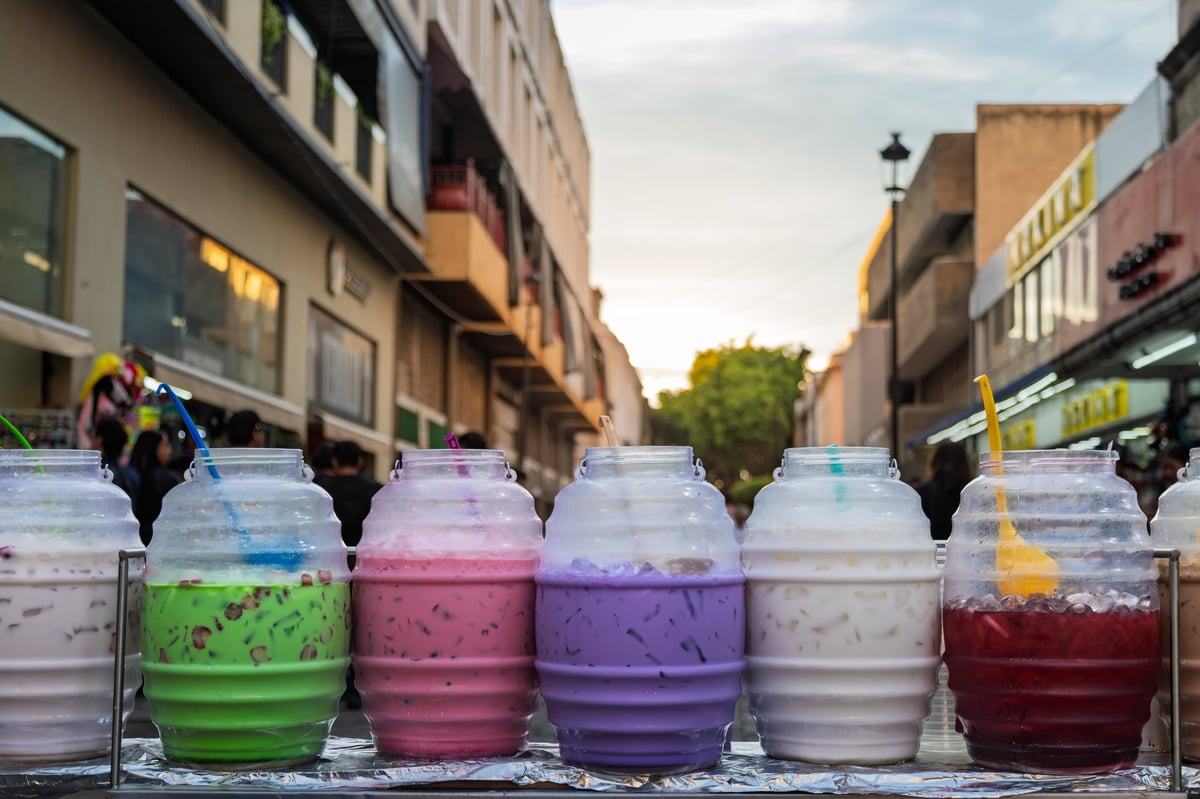 Aguas frescas – traditional fruit drinks in large containers at a street stall